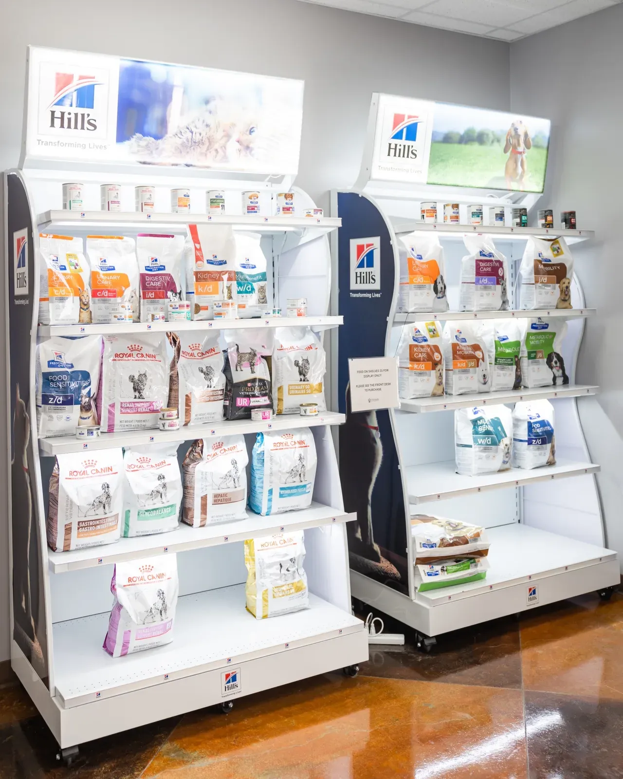 Two white shelf displays holding bags and cans of prescription veterinary pet food