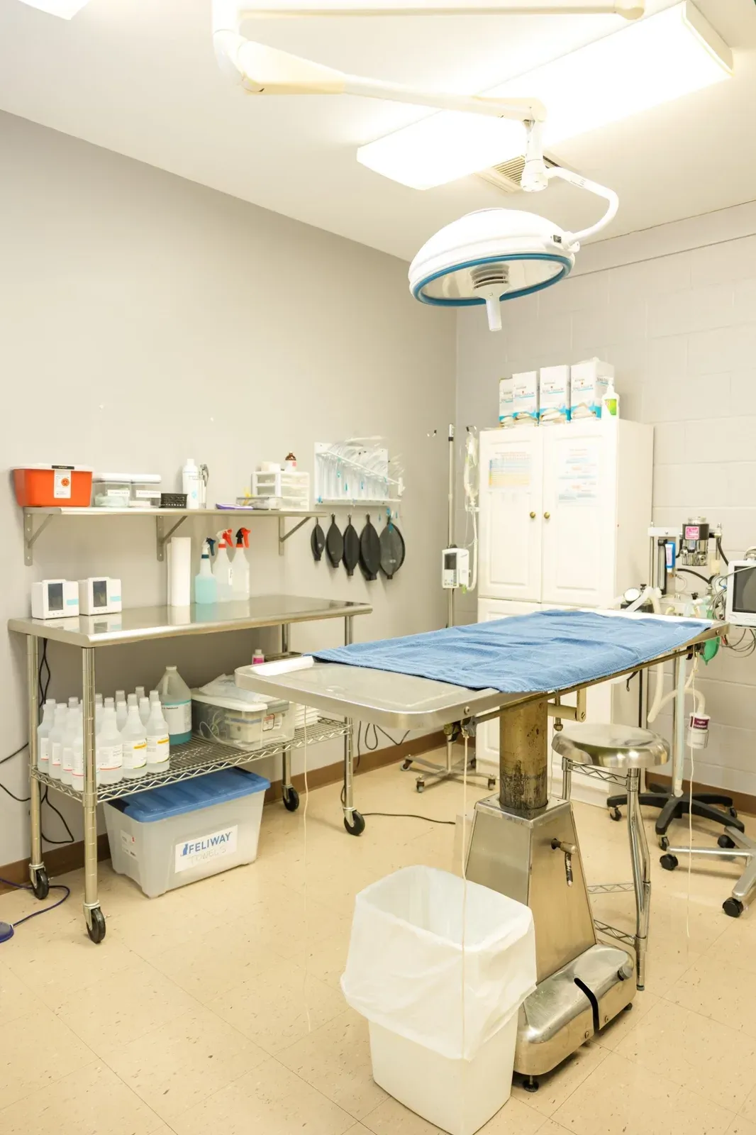 Empty surgery room with a steel table, overhead light, and anesthesia equipment