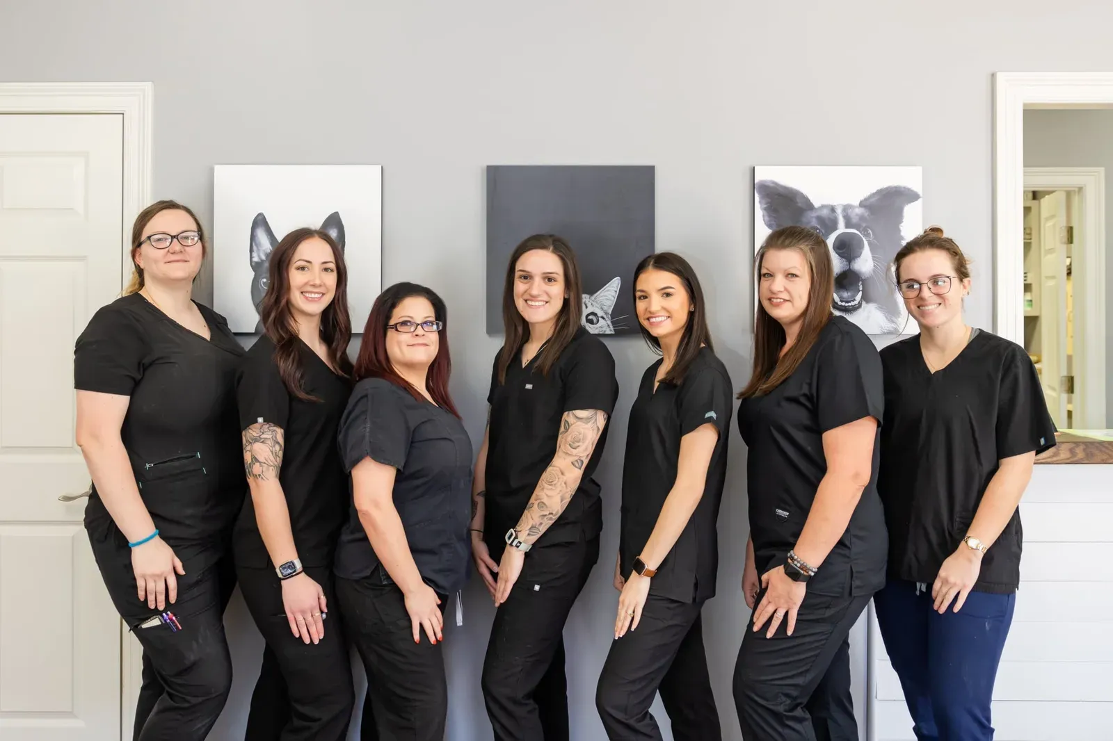 Seven staff members in black scrubs pose together near the front desk