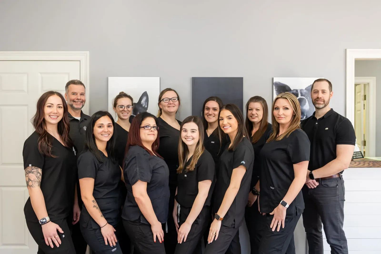Large group of staff in black scrubs posing together in the hospital lobby