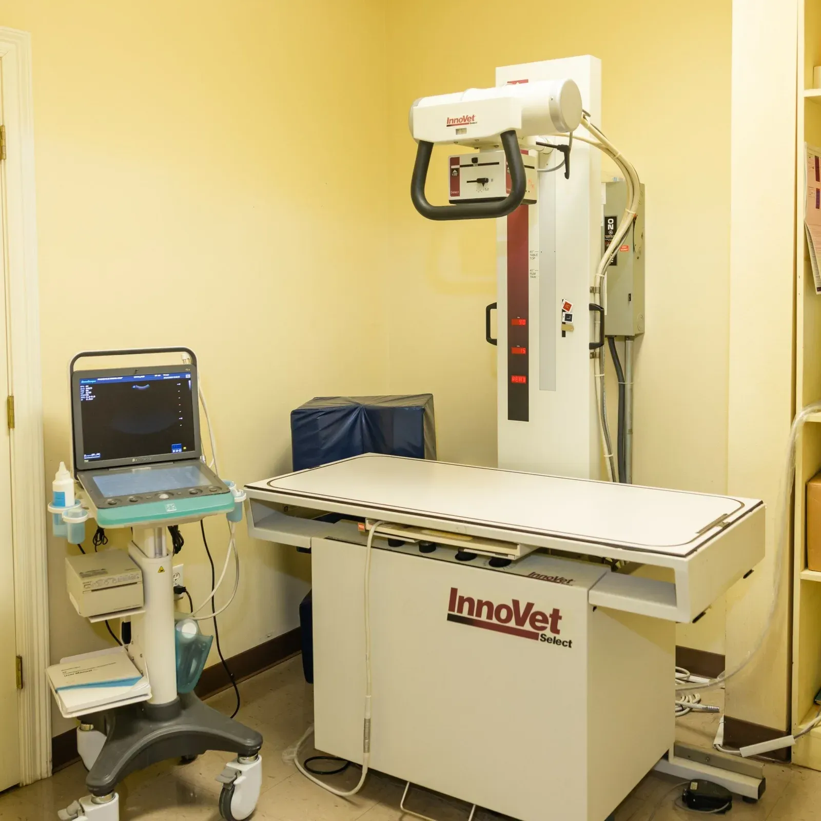 X-ray table with an overhead imaging arm and a rolling ultrasound cart nearby